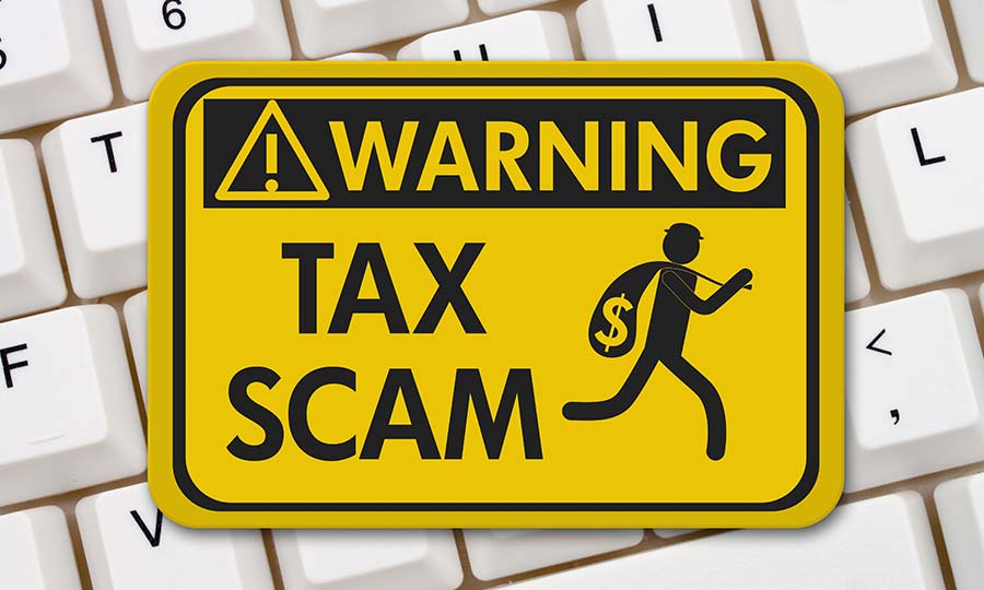 A yellow warning sign on a keyboard that reads Tax Scam